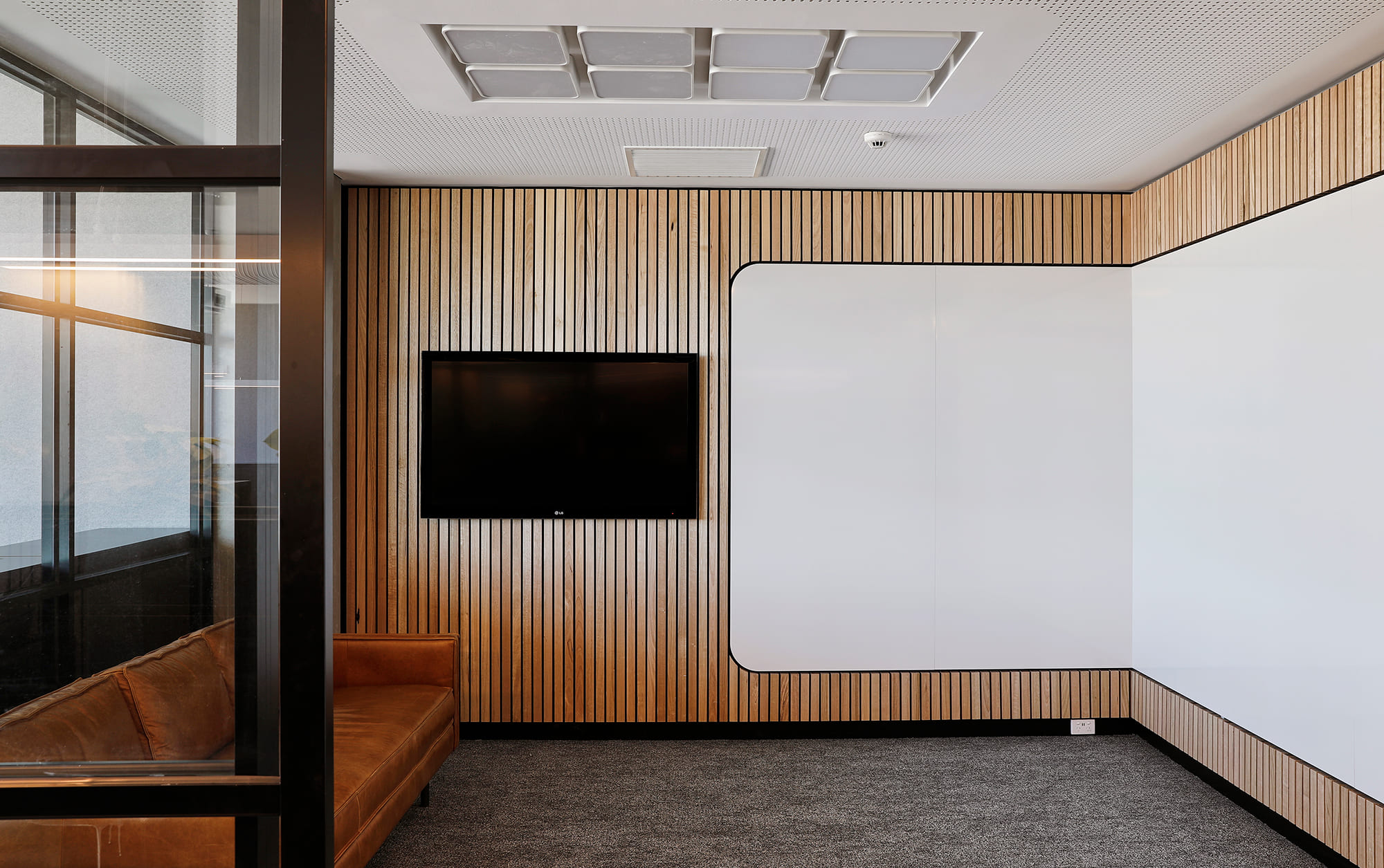 Room with TV, wall-size whiteboard, couch and glass walls